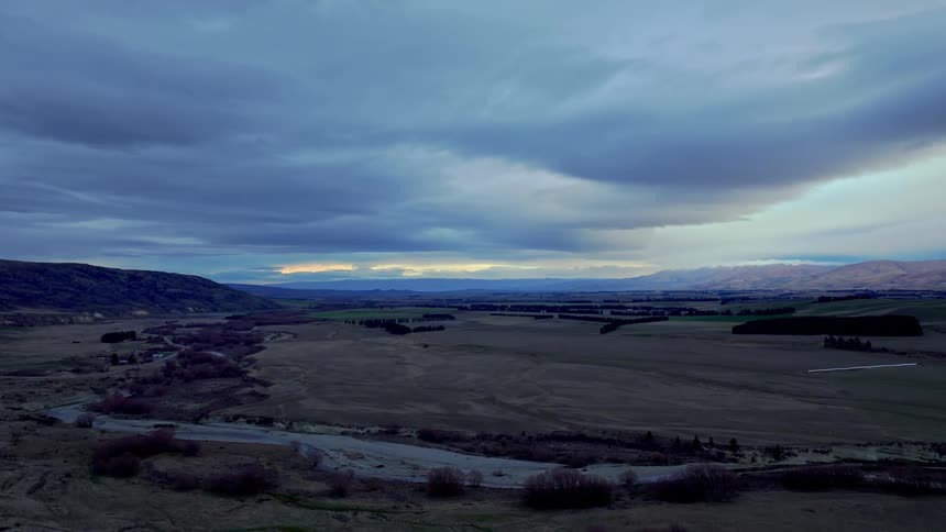 Aerial of a river flowing through a remote grassland near nighttime