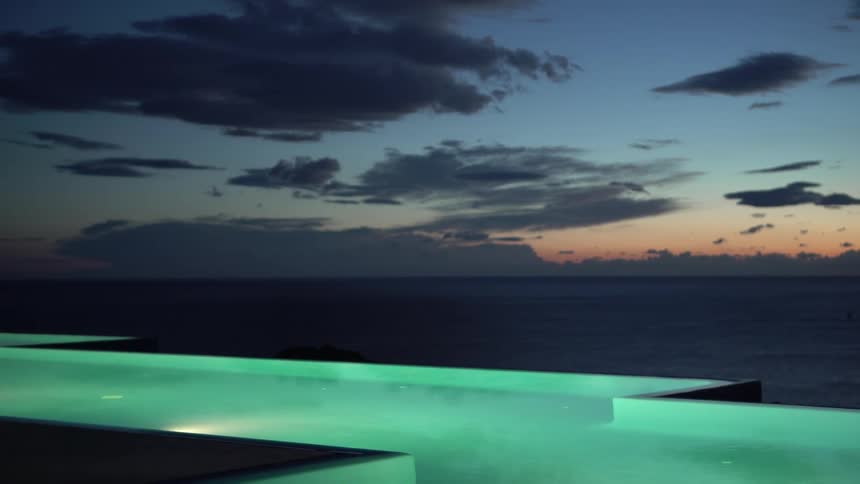 Landscape with a swimming pool illuminated at night by the sea