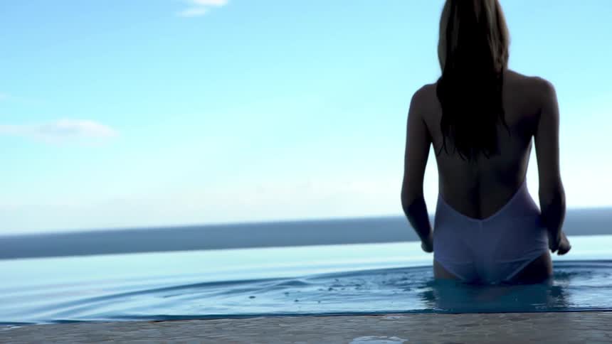 Woman in swimsuit entering and swimming in a pool