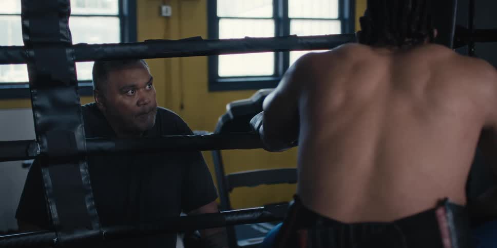 Boxer crouched in a ring talking to his trainer