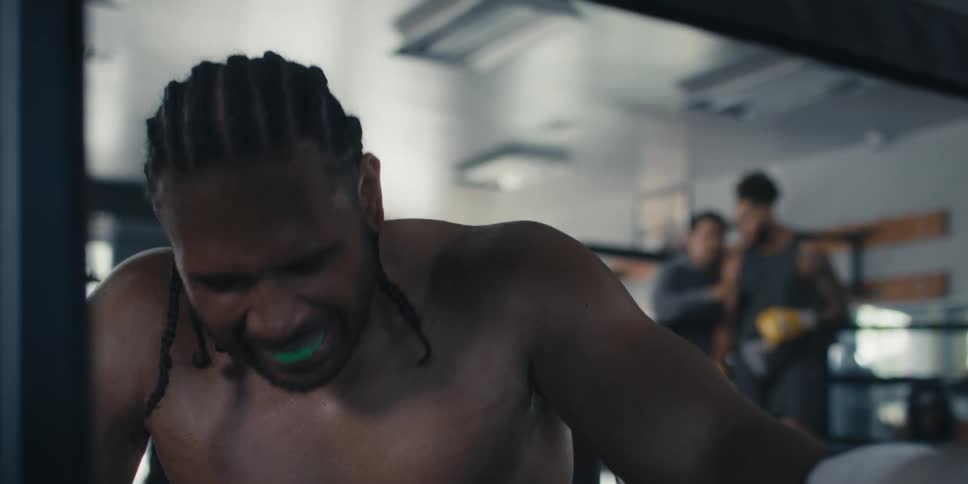 Man taking a deep breath and another boxer standing at the back of the ring