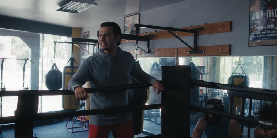 An angry male yelling and talking outside of a boxing ring next to a couple of men