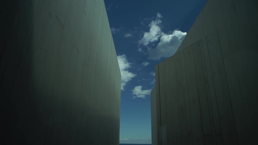 Exterior view of two tall walls against a blue sky with clouds