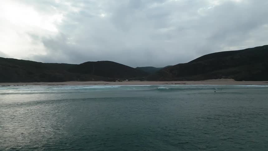 Landscape of a beach on a cloudy day and the silhouette of the coast in the background