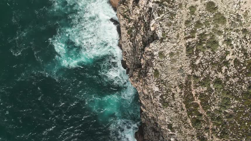 Aerial view of rocky coastline on the edge of a turquoise blue sea