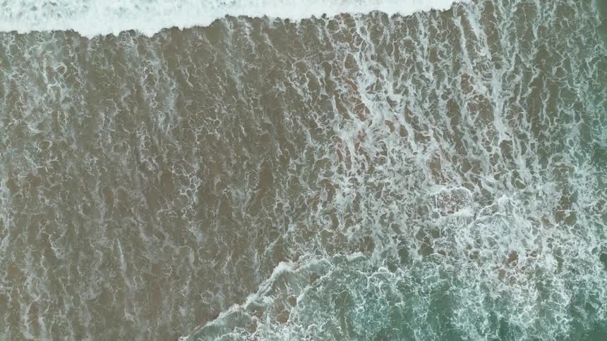 Successive foamy waves roll onto a beach