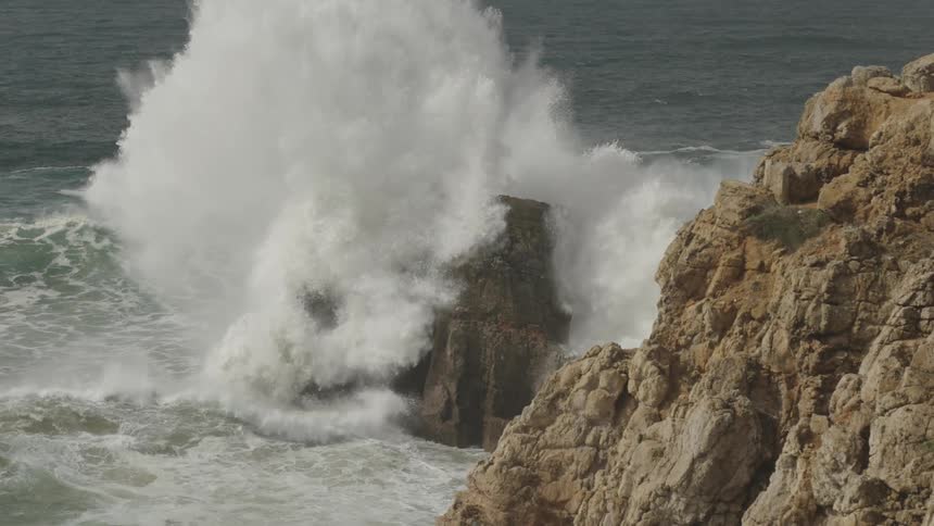 Strong wave with foam hitting rocks