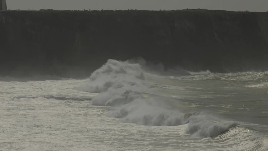 Waves foam while flowing onto the shore on a foggy day