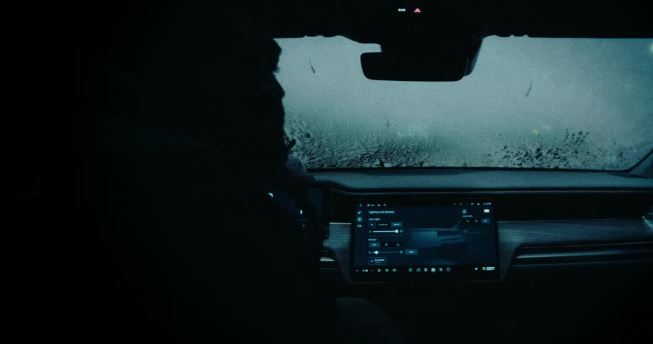A person sitting in the drivers seat of a car focusing on the dashboard and a frosted car window