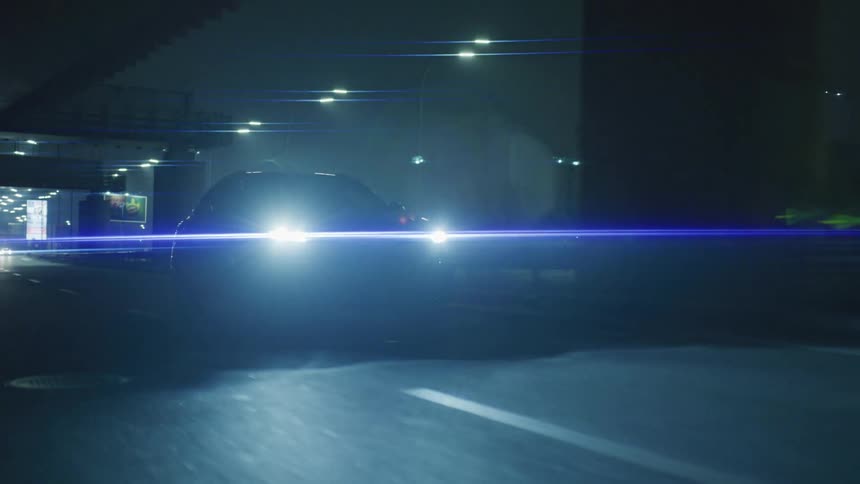 A car driving on a road at night with street lights in the background