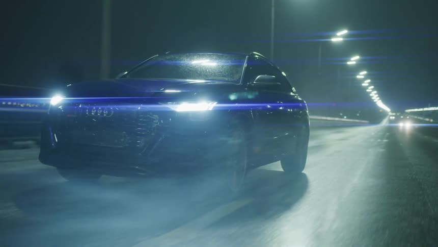 A car drives on a wet road at night with its headlights on