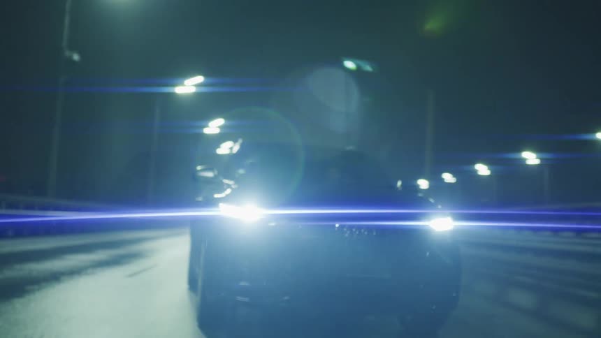 Car driving at night with headlights on illuminating the road ahead