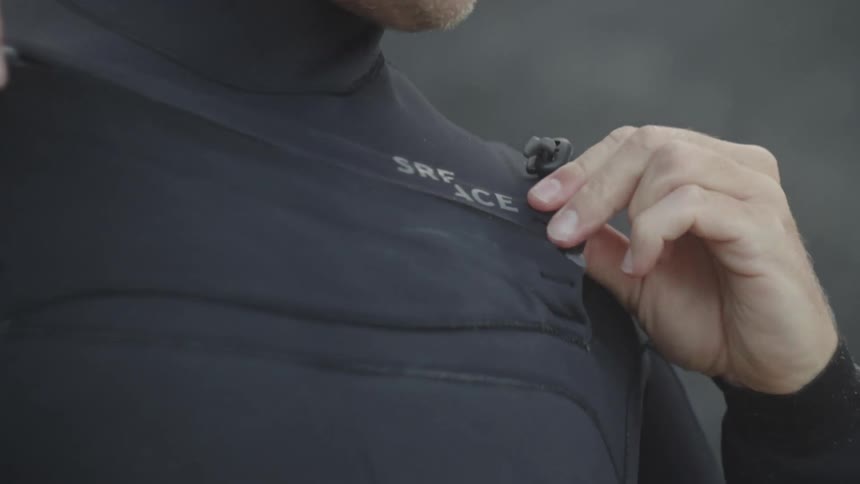 Hands of a surfer zipping up his swimsuit