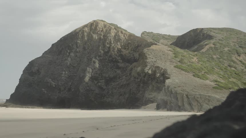 Rocky and arid coastline on the edge of the sandy beach