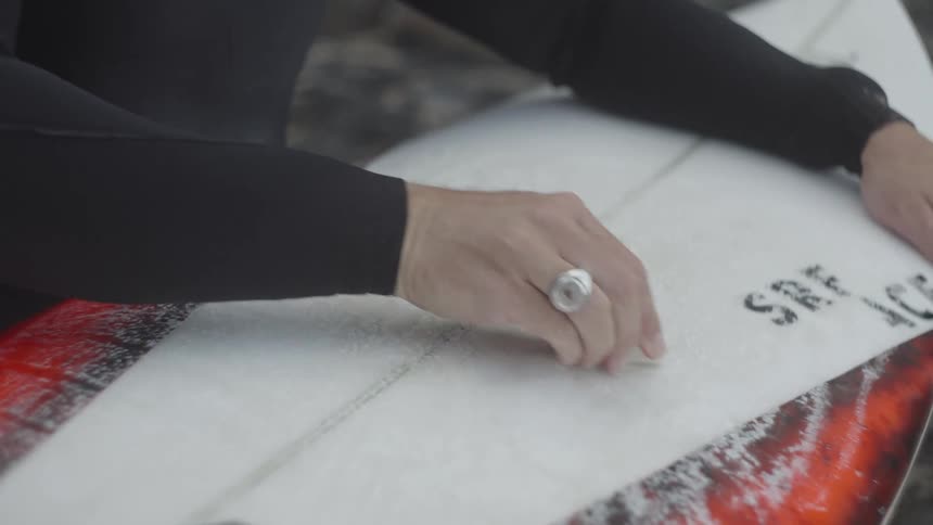 Surfer waxing his board