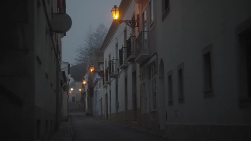 Corridor of a narrow residential neighborhood with lights on