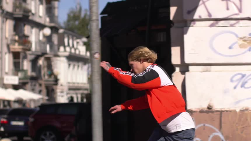 Person in a red and white jacket skateboarding on an urban street