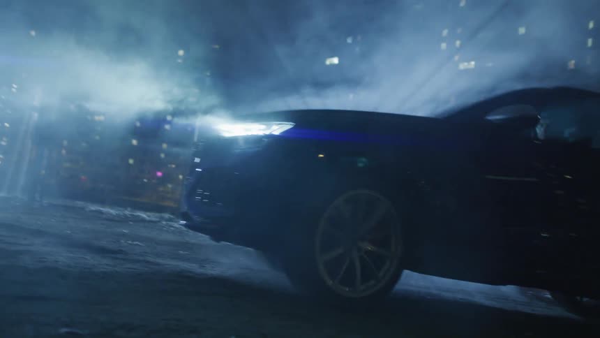 Luxury car driving down a street at night