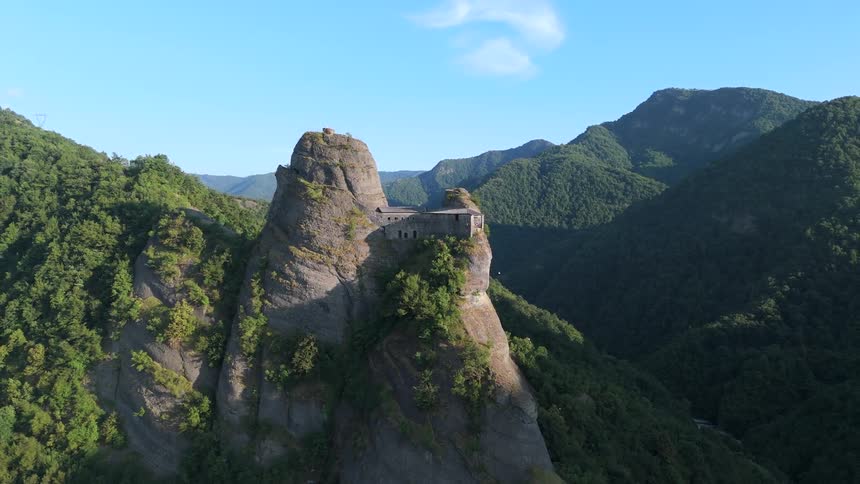 Aerial of a fortress built on top of a mountain rock on a sunny day