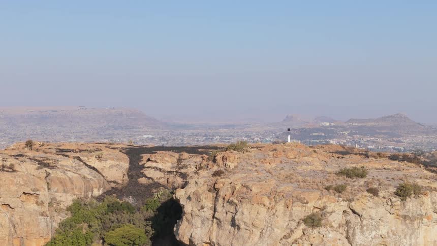 Aerial landscape of a mountainous and rocky valley with a city in the background