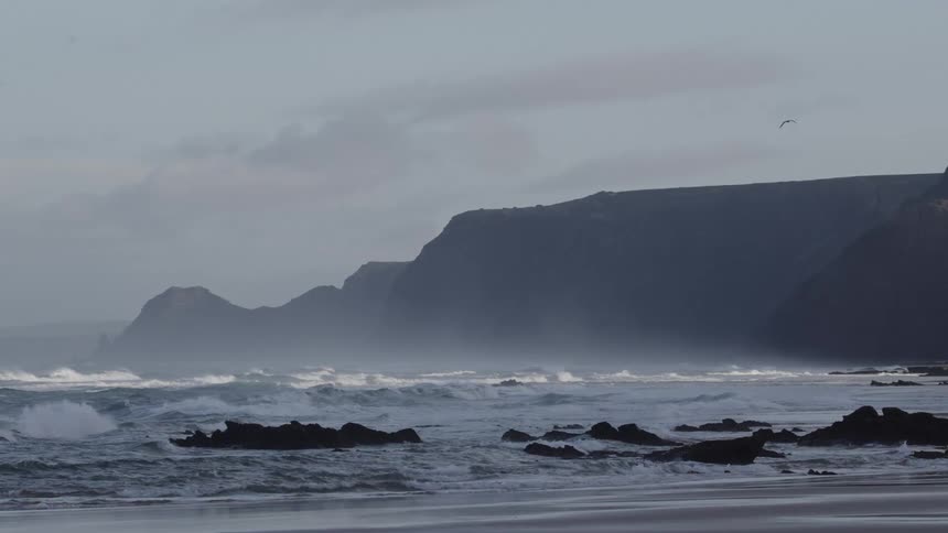 Ocean waves roll into the beach on mostly sunny day