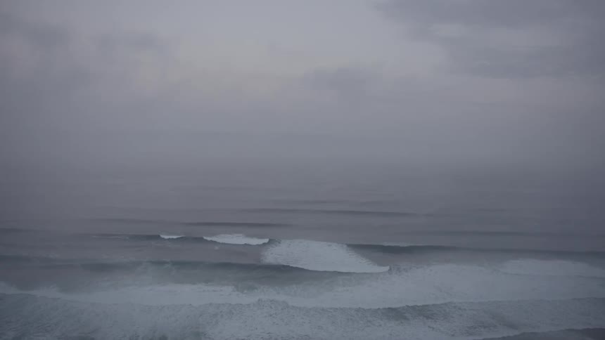 Landscape of a vast ocean with several waves on a cloudy day