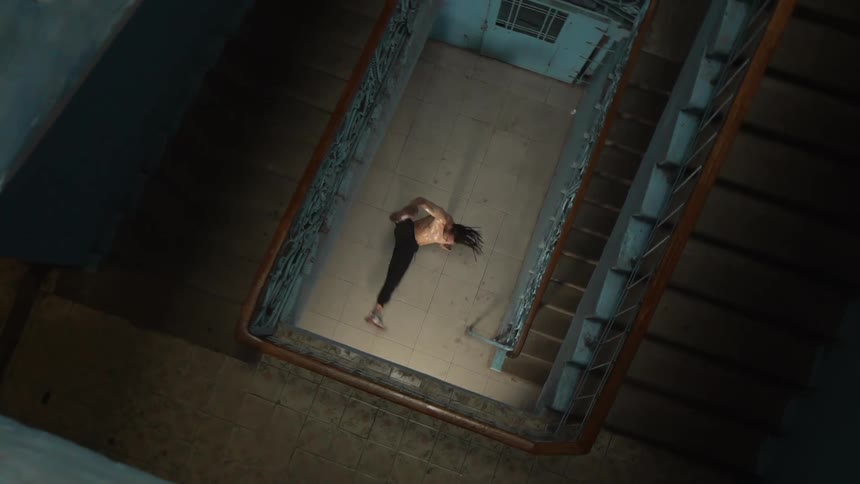 Man break dances at the bottom of a stairwell