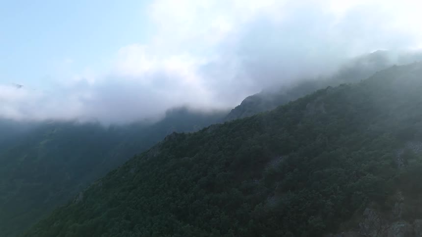 Aerial view of a mountain valley with vegetation and low clouds