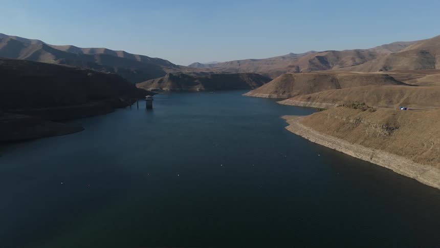 Aerial view of a long bridge above a lake and connecting mountains