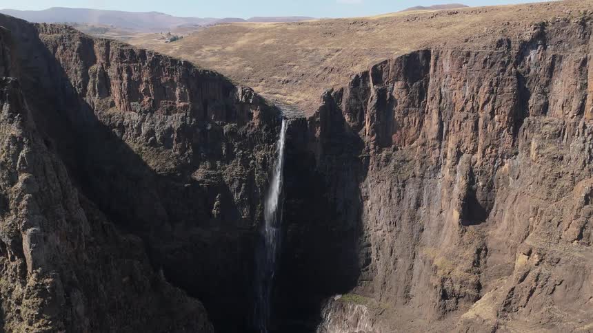 A tall waterfall cascades down a steep rocky cliff face