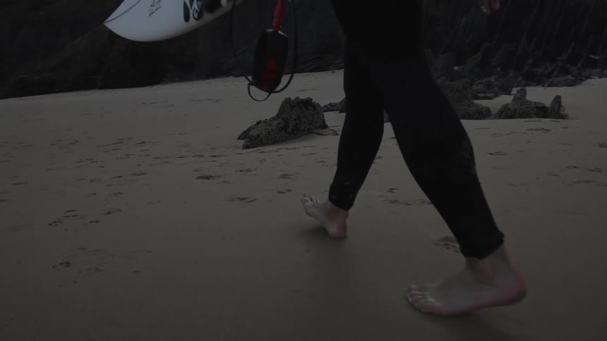 Feet of a surfer walking on the sand at the beach