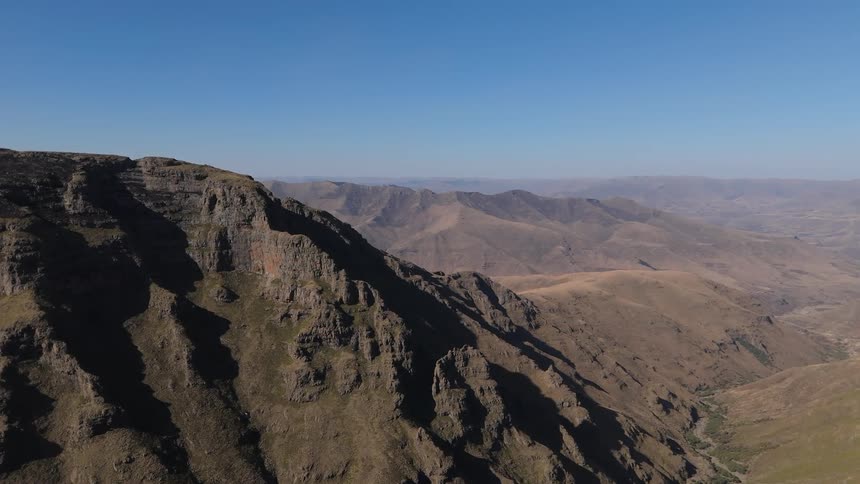 Aerial panorama of a vast mountain valley against a clear blue sky