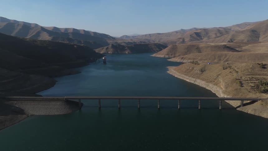 Landscape of a dam on a reservoir with mountains in the background