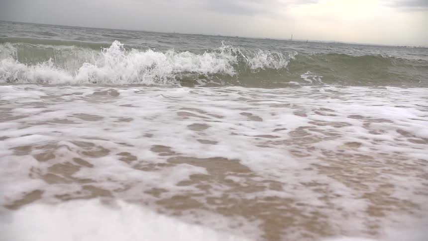 Waves crashing on a shore on a cloudy day