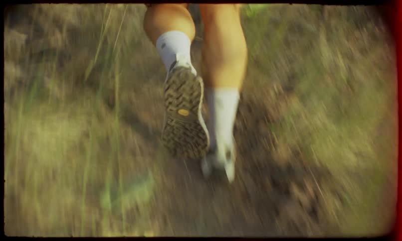 Female jogger runs along a dirt track on a summer day