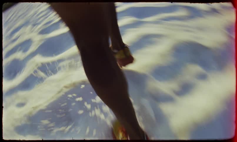 Man wearing shorts runs across snow between conifer dotted slopes on a cloudy day