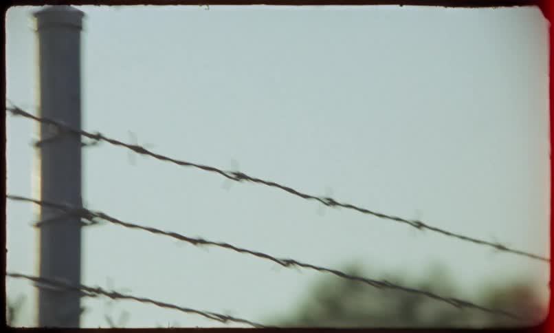 Hill towers over a chain link fence topped with barbed wire