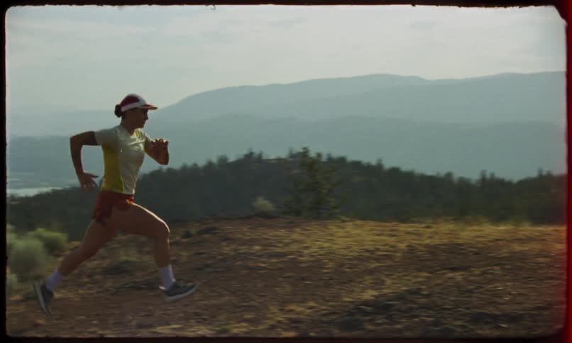 Woman runs past a forested slope overlooking a coastal city on a foggy day