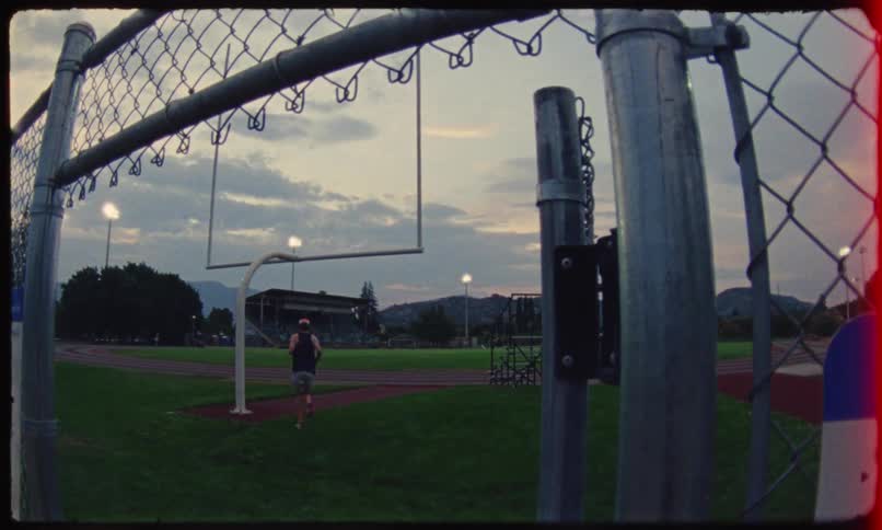 Person opening a gate and running towards an athletics track