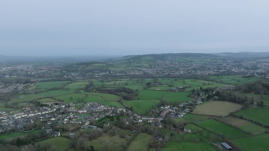 An aerial view captures a sprawling countryside dotted with homes farms and rolling hills