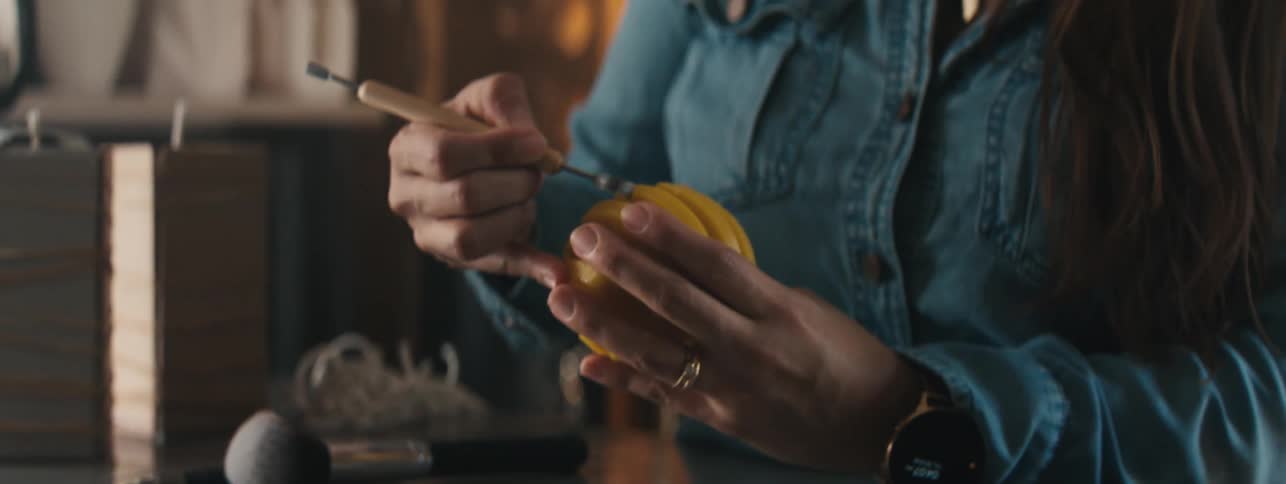 Close up of a womans hands carving a yellow candle