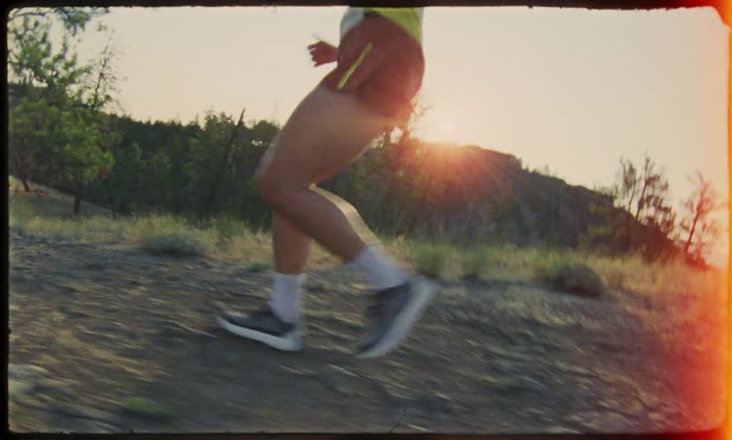 A jogger in shorts runs down a dirt path in a nature