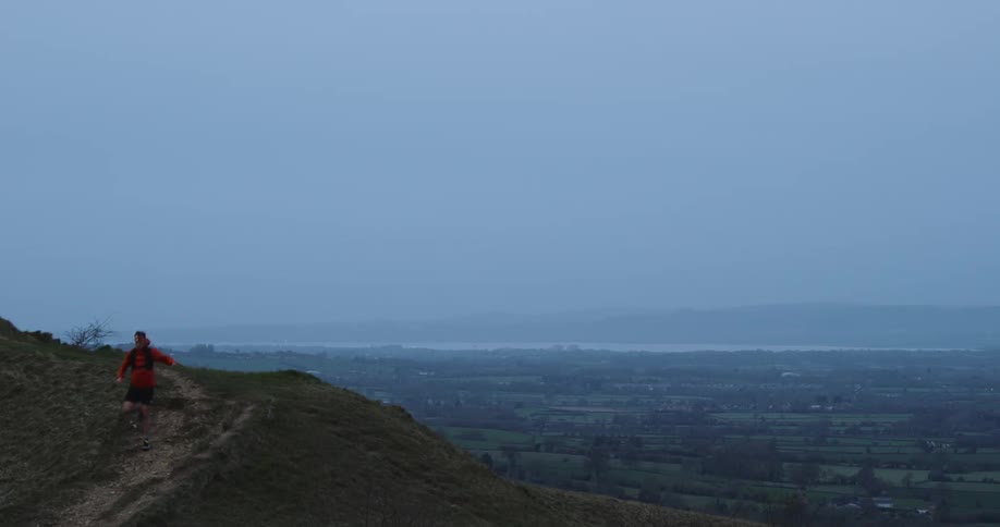 Man running down a mountain on a cloudy day