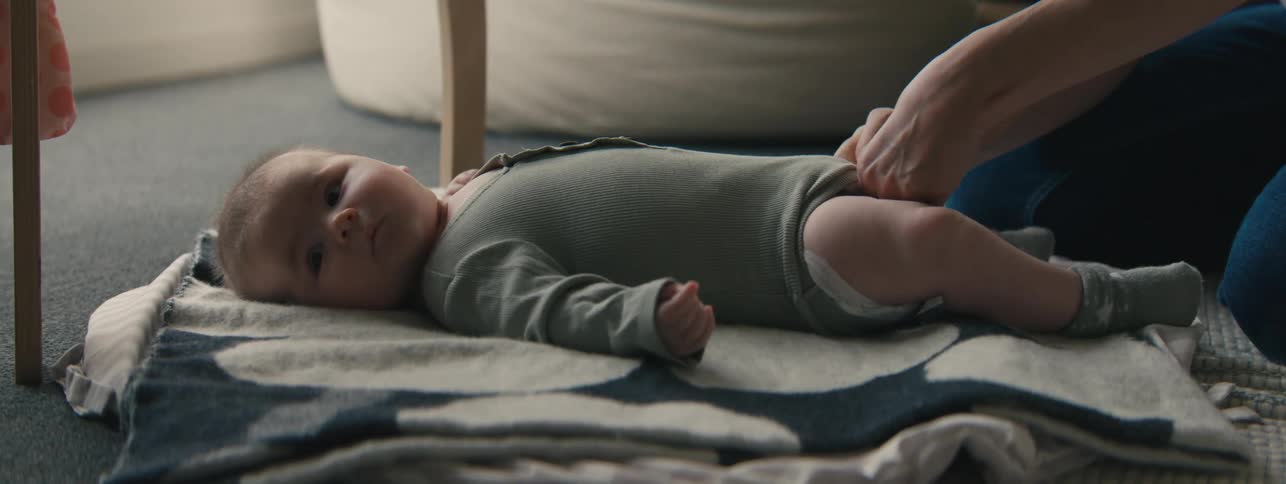 A parent is changing a babys diaper on a blanket