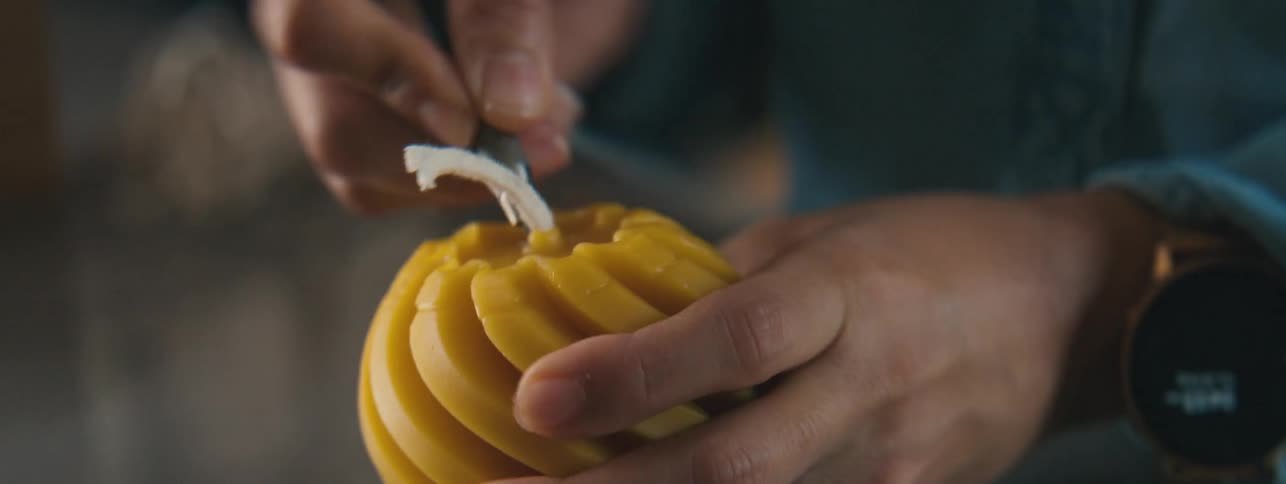 Womans hand working on a yellowish round candle