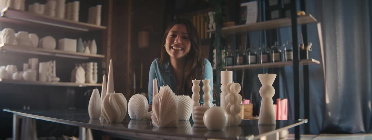 A woman smiling and in front of her there is a table full of craft objects