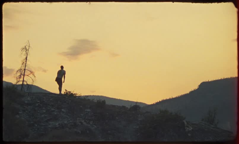 Silhouette of a person on a mountain peak by the sea starting to run