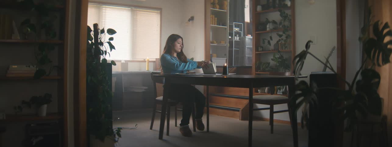 Woman walking down the stairs of a room and sitting at the table