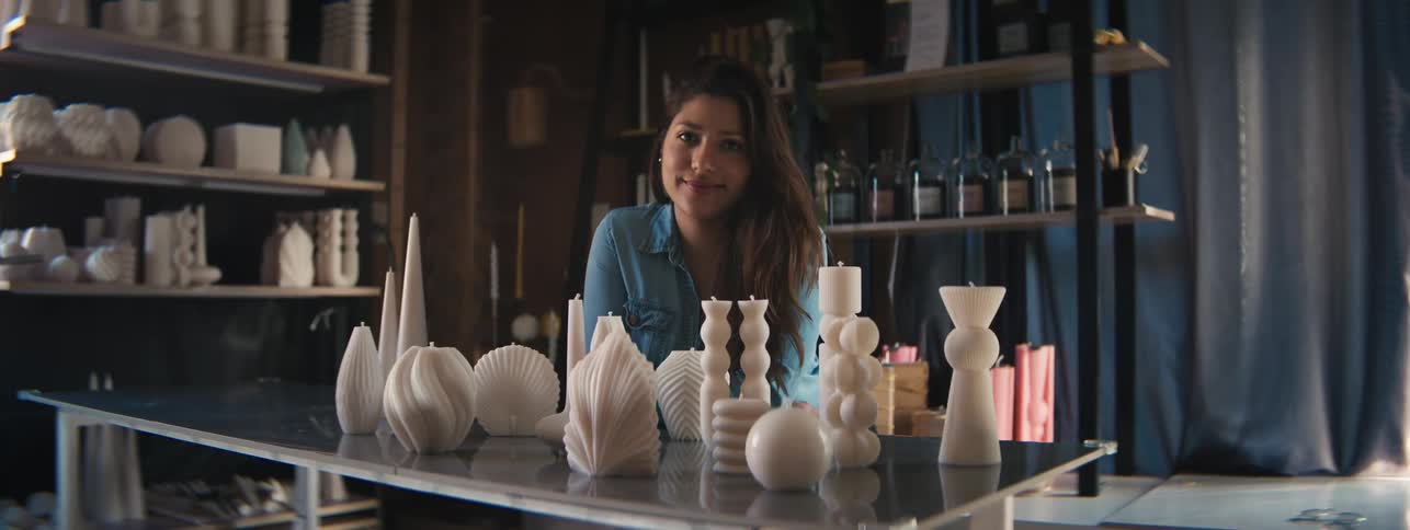 Craftswoman posing with her artistic works of different candle molds on a table