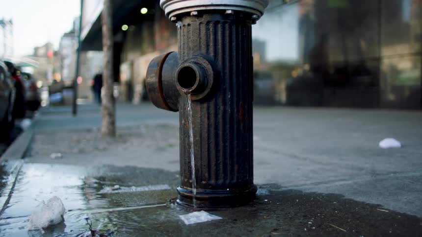 A fire hydrant leaks water onto the pavement